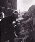 DOISNEAU (Robert). | Gardien de la paix en tenue, grenade à la main, barricade de Belleville.